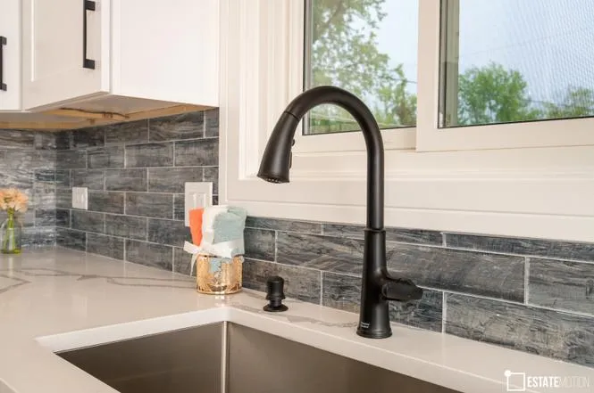 A stylish kitchen sink with a black faucet, situated below a window, enhancing the room's brightness and appeal.