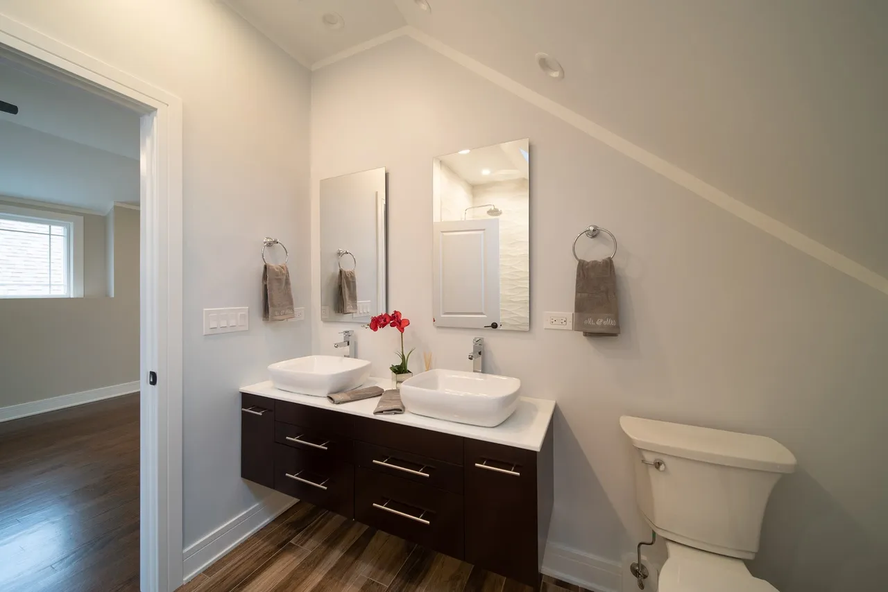 A stylish bathroom with dual sinks and a mirror, emphasizing a contemporary aesthetic and ample space for use.