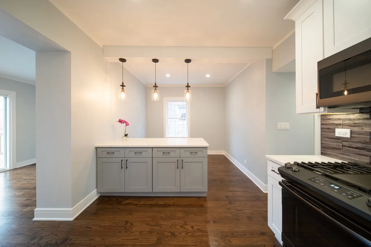Contemporary kitchen design with white cabinetry and polished wood floors, emphasizing a fresh and elegant look.